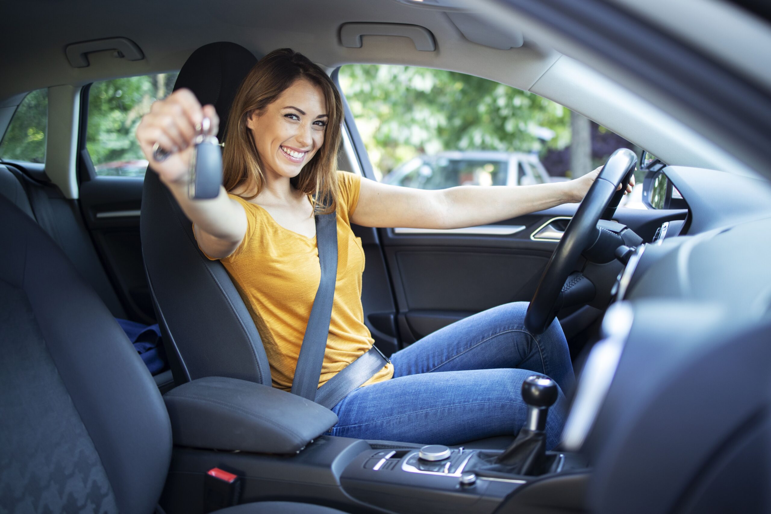 Beautiful female women driver sitting in her vehicle and holding car keys ready for a drive.